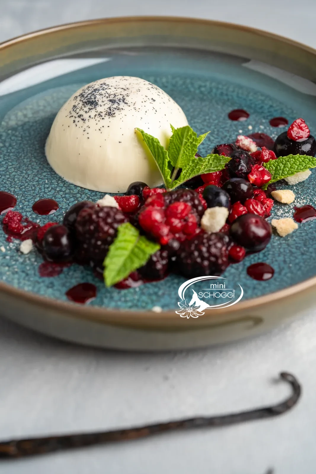 Panna cotta démoulée avec fruits rouges et menthe sur une assiette bleue