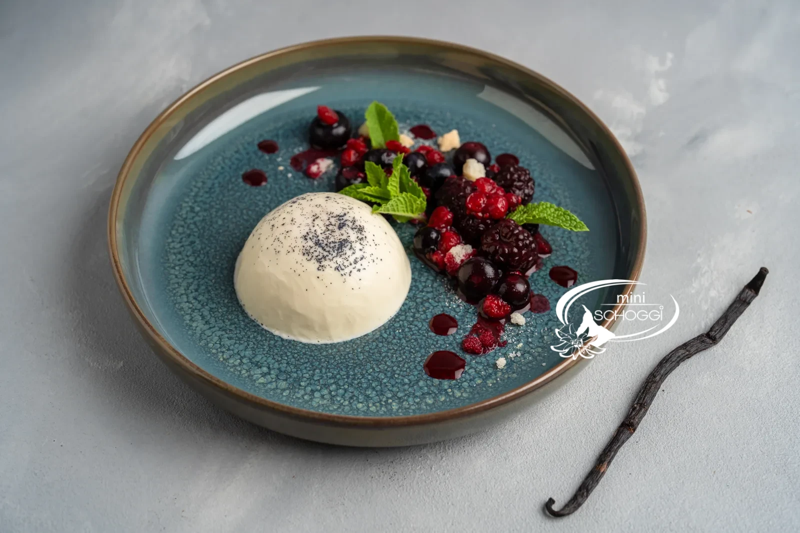 Panna cotta démoulée avec fruits rouges et menthe sur une assiette bleue
