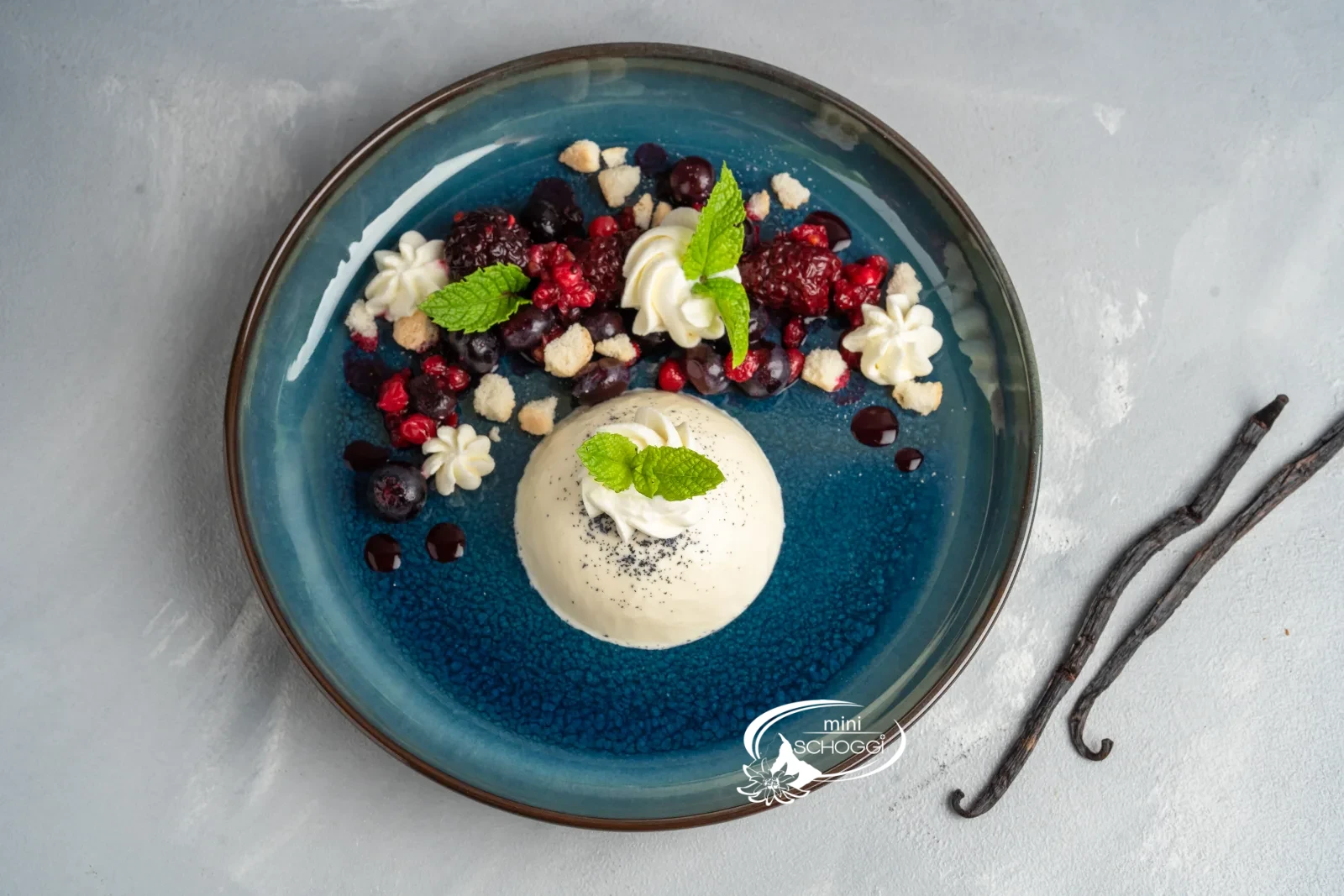 Panna cotta démoulée avec fruits rouges et menthe sur une assiette bleue