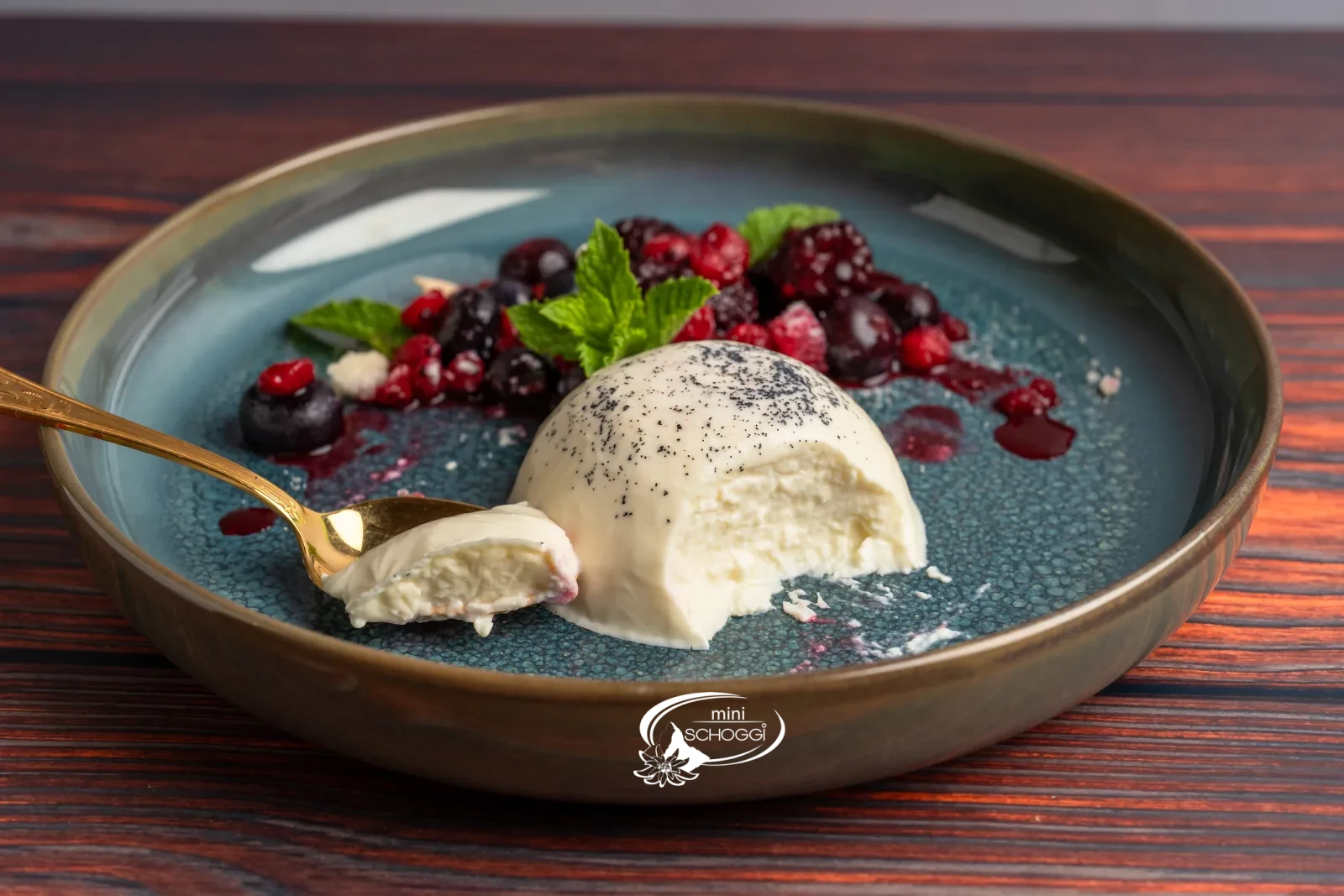 Panna cotta démoulée avec fruits rouges et menthe sur une assiette bleue