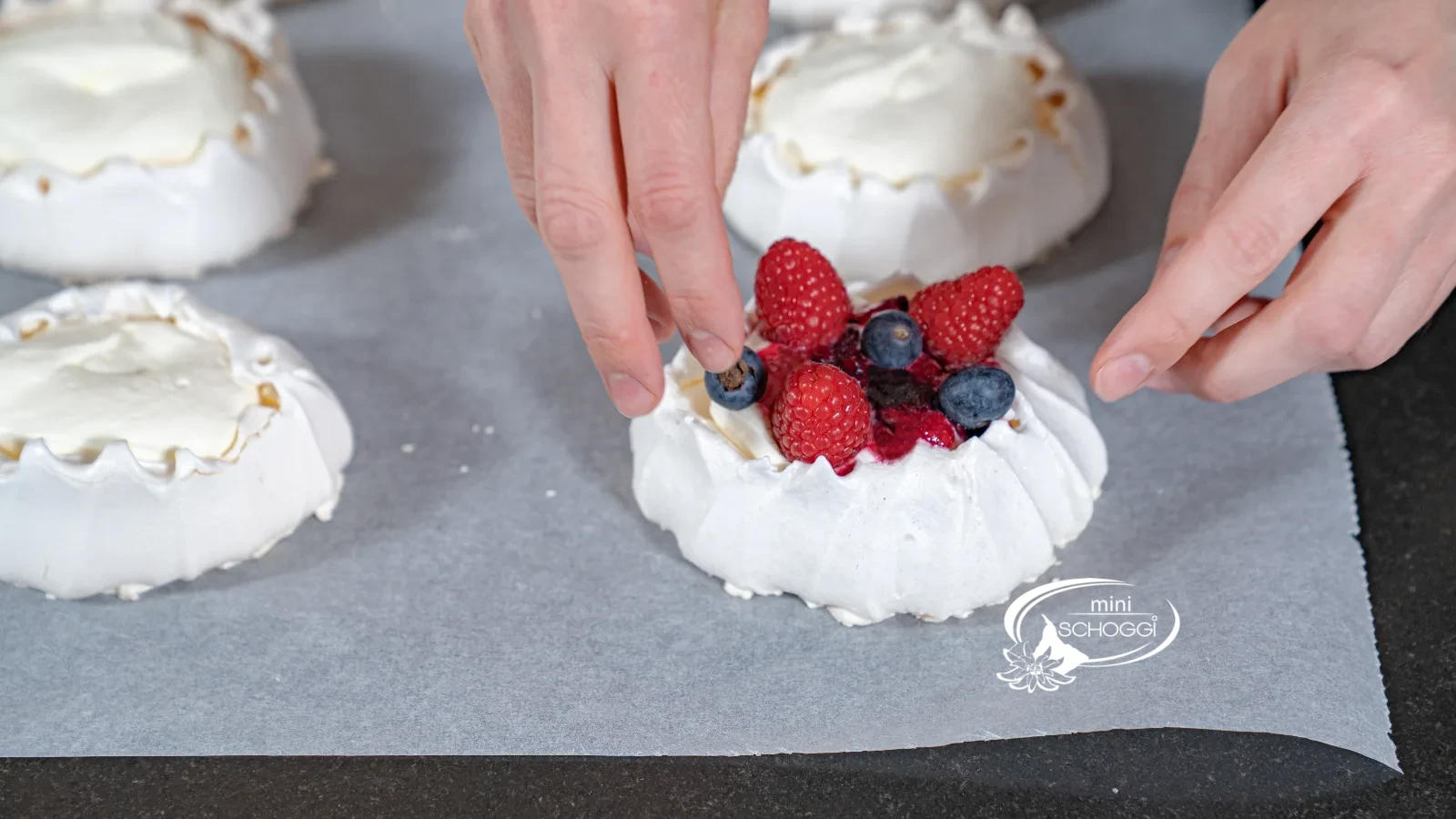 Des framboises et des myrtilles fraîches sont disposées à la main sur la pavlova garnie