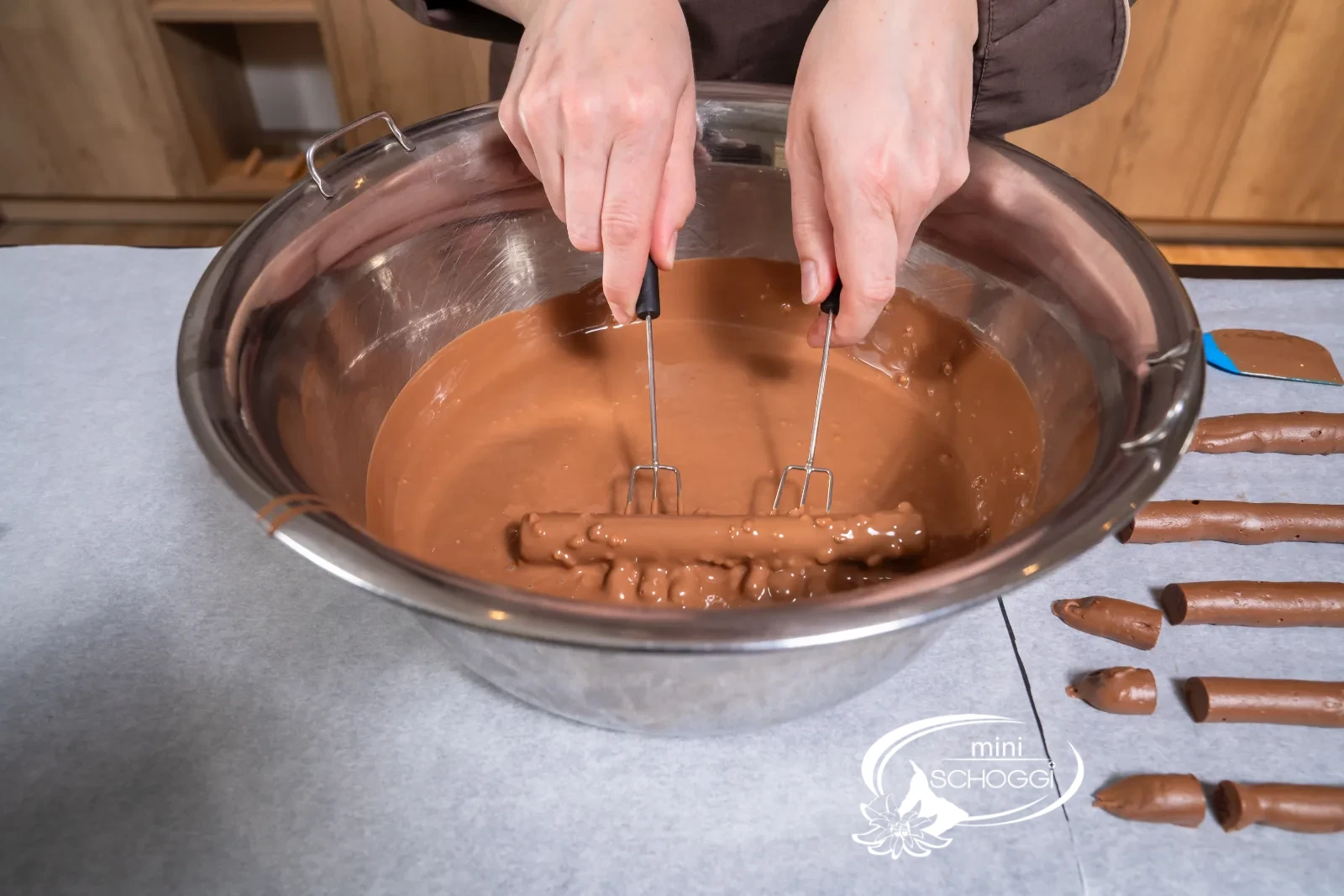 A stick is dipped into the couverture with two dipping forks