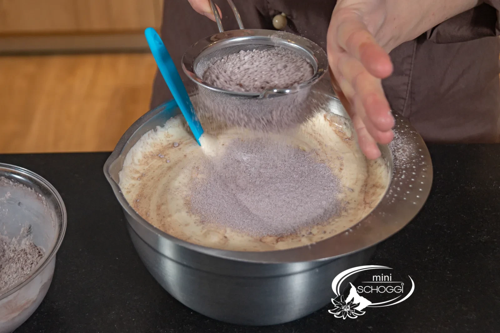 Polvere di cacao e farina vengono setacciate nella schiuma di uova e incorporate con la spatola in gomma