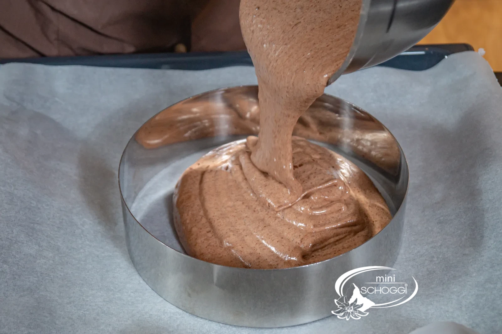 L'impasto del pan di Spagna al cioccolato viene versato nell'anello per torta sulla teglia