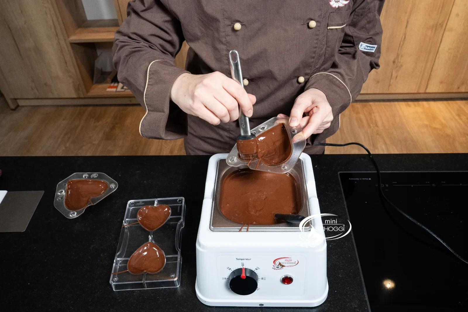 Lo stampo a cuore viene spennellato con la copertura di cioccolato usando il pennello in silicone