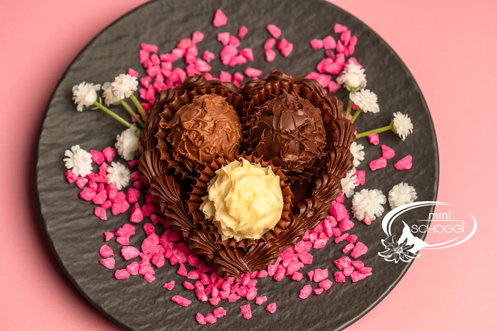 Cuori di cioccolato riempiti di Truffes, uno confezionato in sacchetto trasparente, su legno scuro