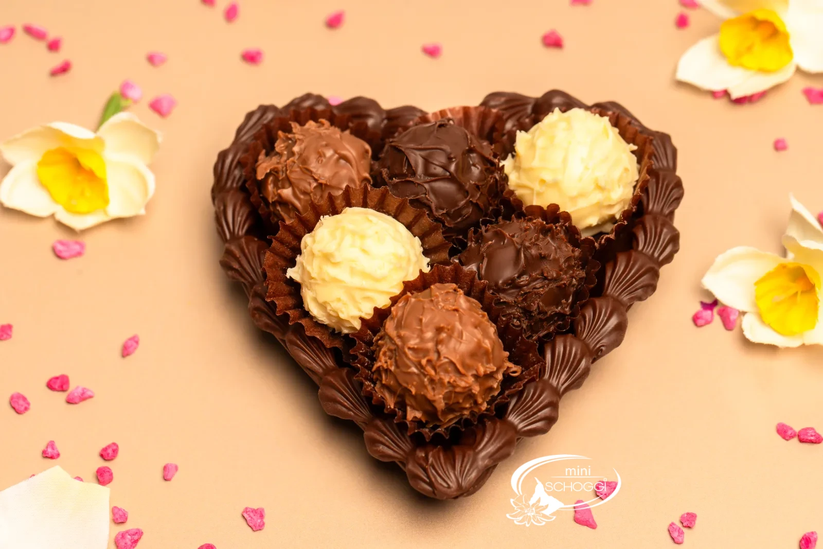 Cuori di cioccolato riempiti di Truffes, uno confezionato in sacchetto trasparente, su legno scuro