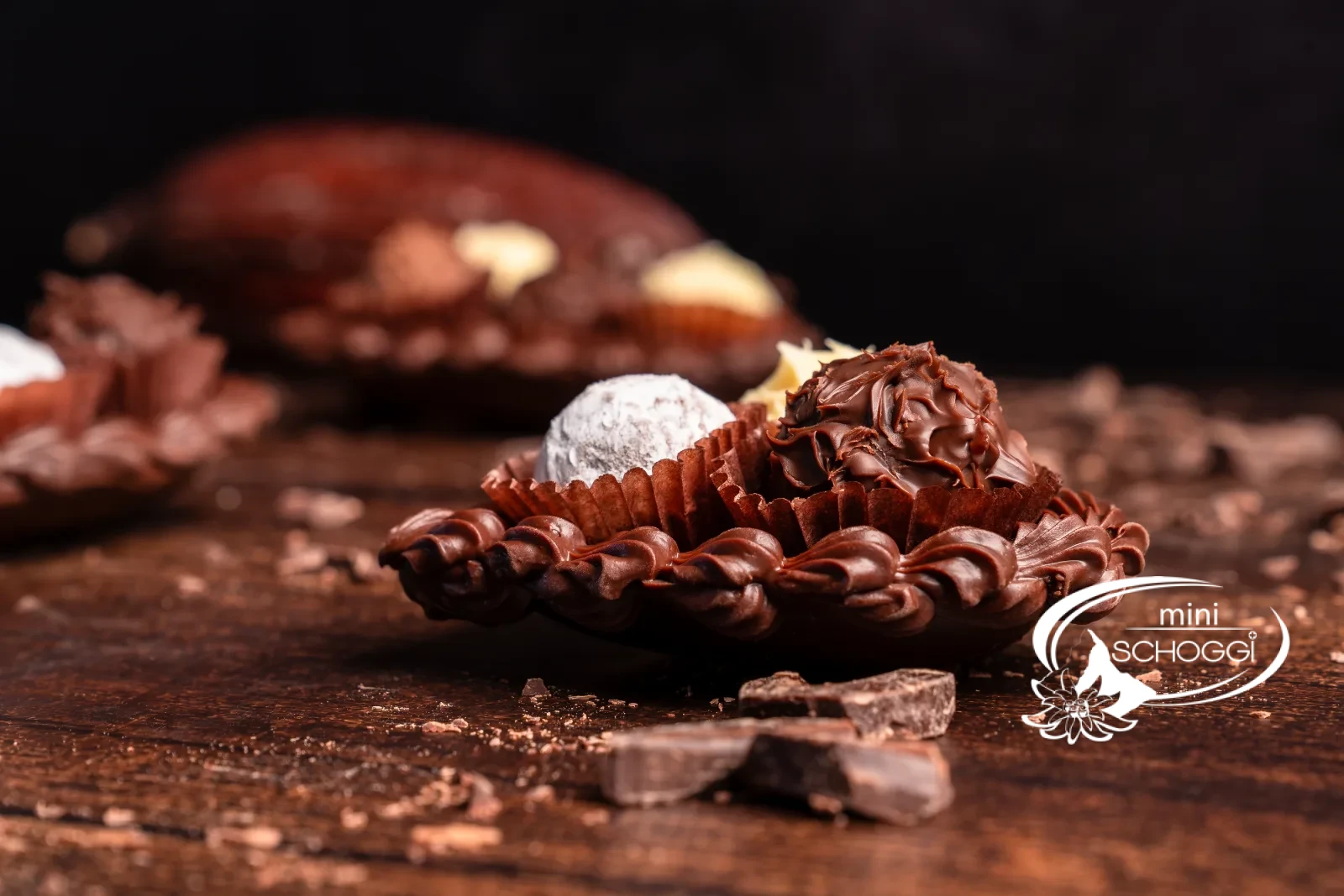 Cuori di cioccolato riempiti di Truffes, uno confezionato in sacchetto trasparente, su legno scuro