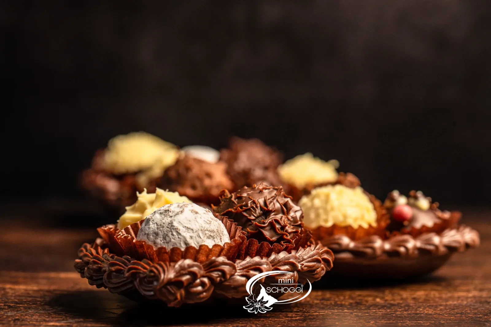 Cuori di cioccolato riempiti di Truffes, uno confezionato in sacchetto trasparente, su legno scuro