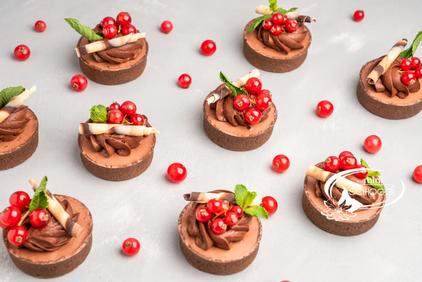 Tortino al cioccolato con rosette di mousse, ribes e menta su un tavolo chiaro