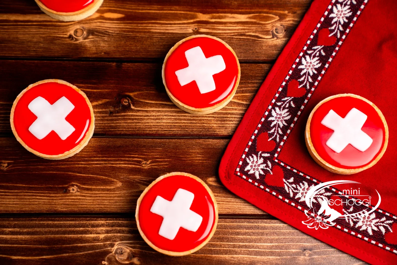 Carac svizzeri con fondant rosso e croce bianca su tavolo di legno scuro