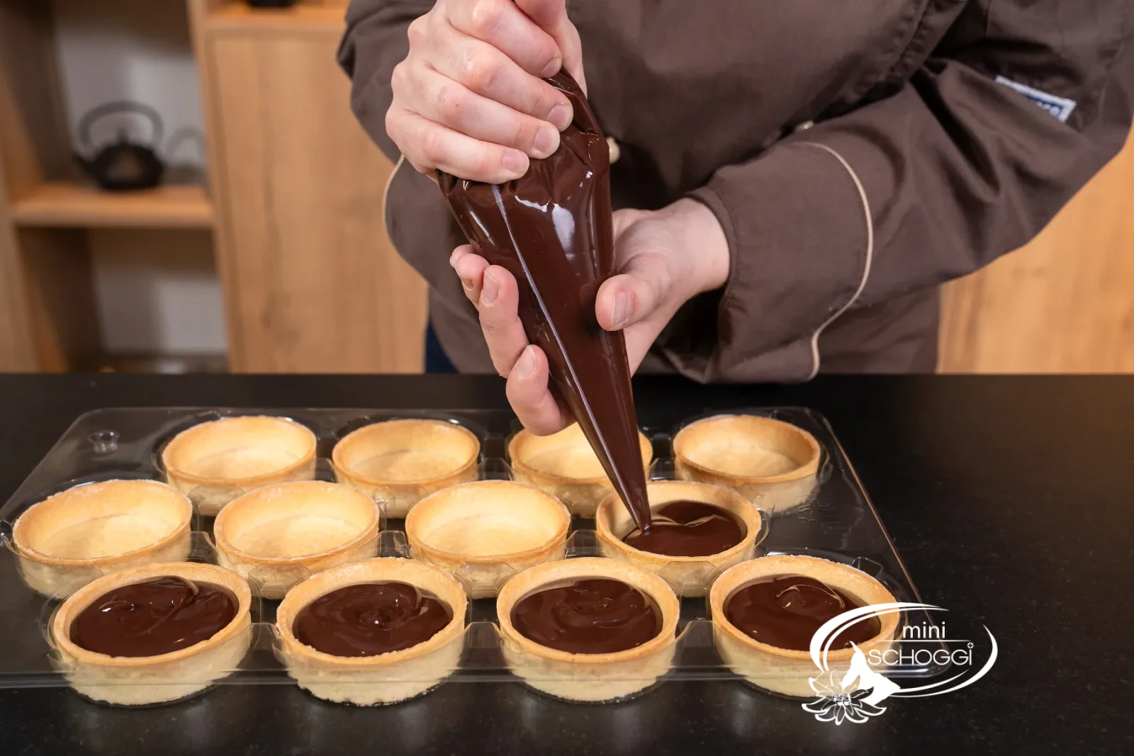 Una fila di tartelette viene riempita una dopo l'altra con la Ganache