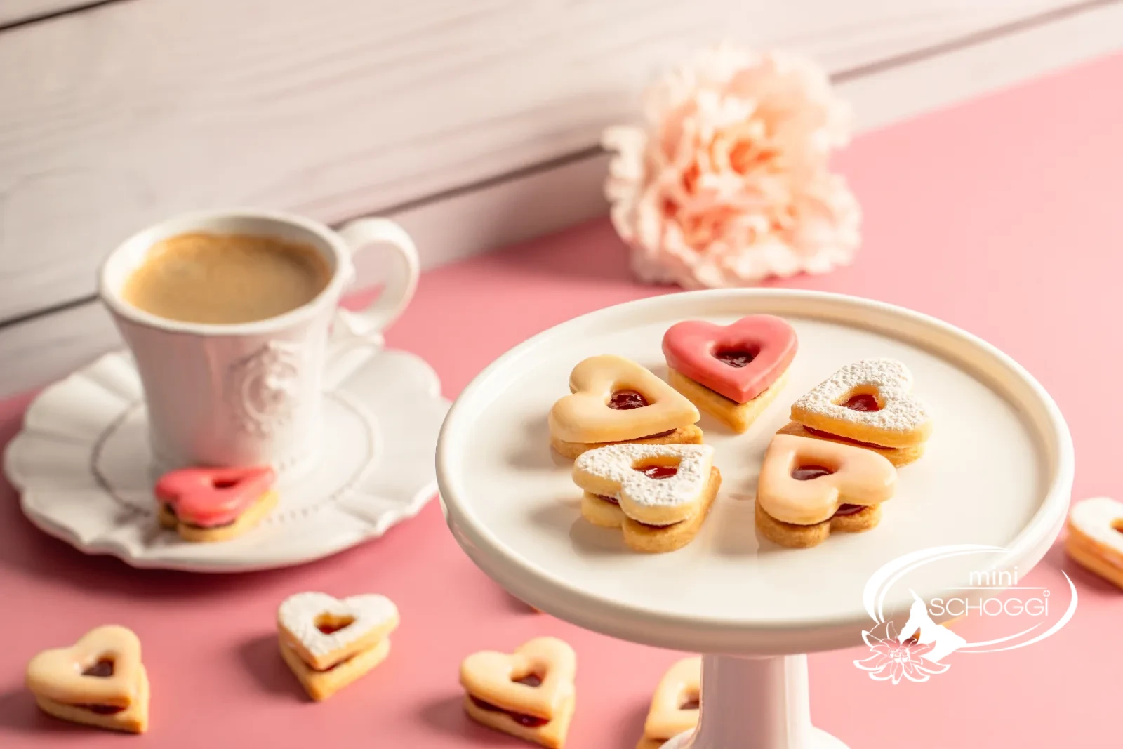 Cuori occhi di bue con glassa rosa e confettura accanto a una tazza di caffè