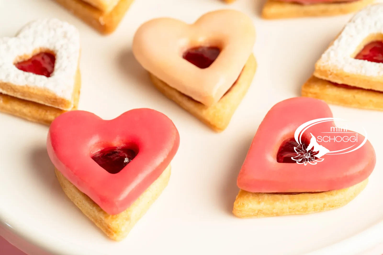 Cuori occhi di bue con glassa rosa e confettura accanto a una tazza di caffè