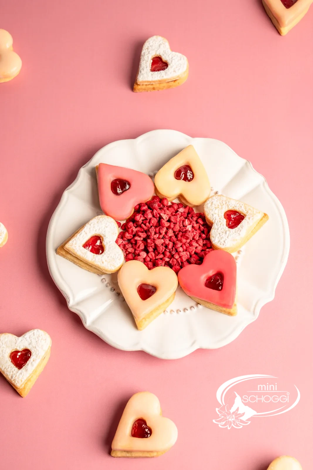 Cuori occhi di bue con glassa rosa e confettura accanto a una tazza di caffè