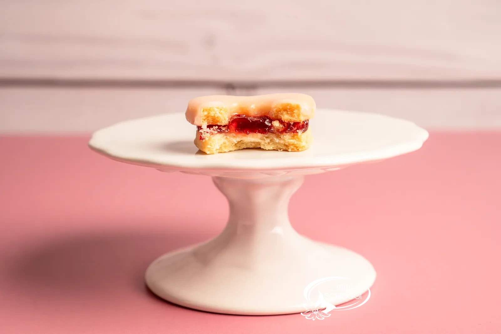 Cuori occhi di bue con glassa rosa e confettura accanto a una tazza di caffè