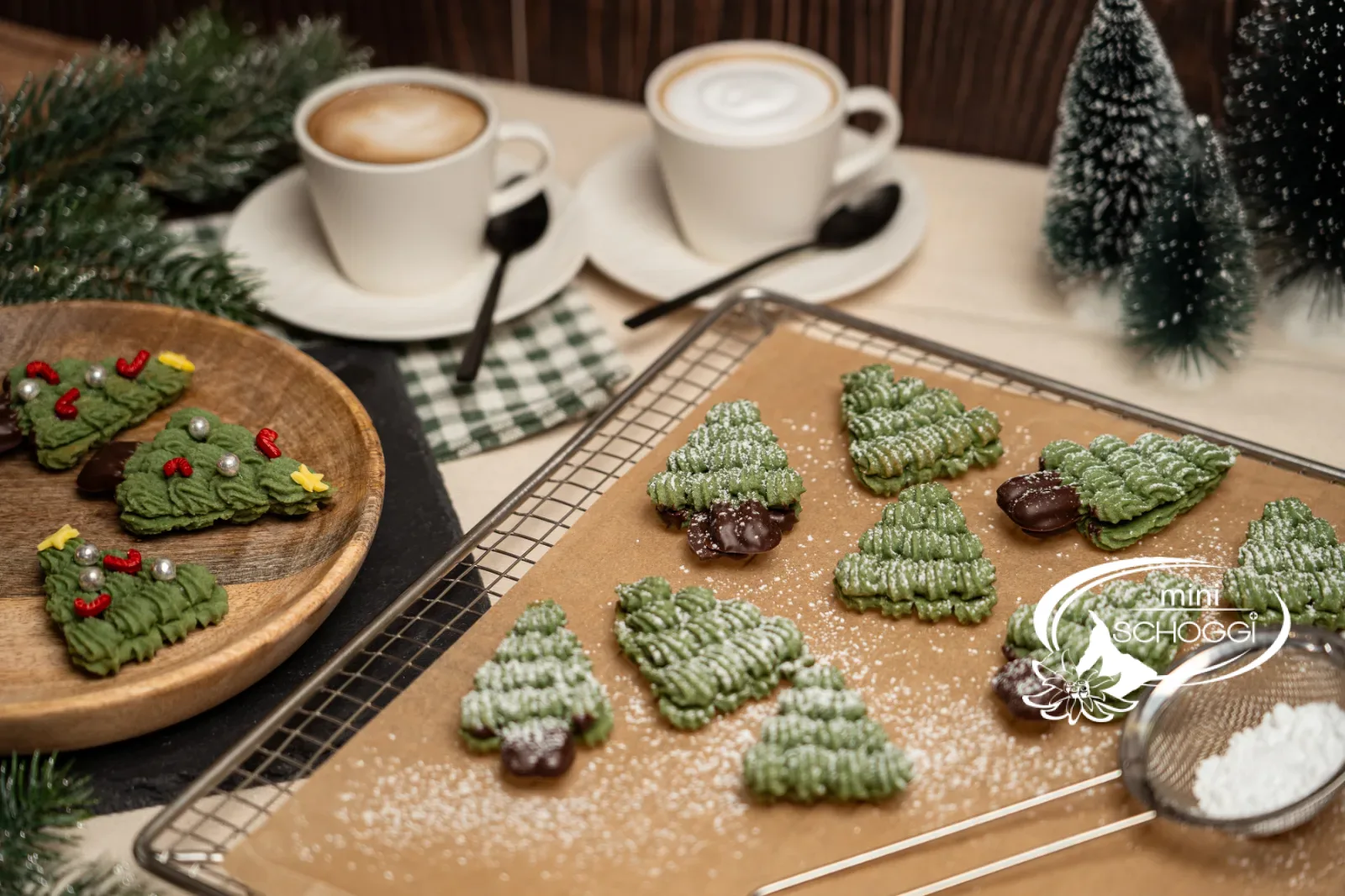 Sapins décorés aux quetsches et à la cannelle sur une planche en bois à côté d'un cappuccino