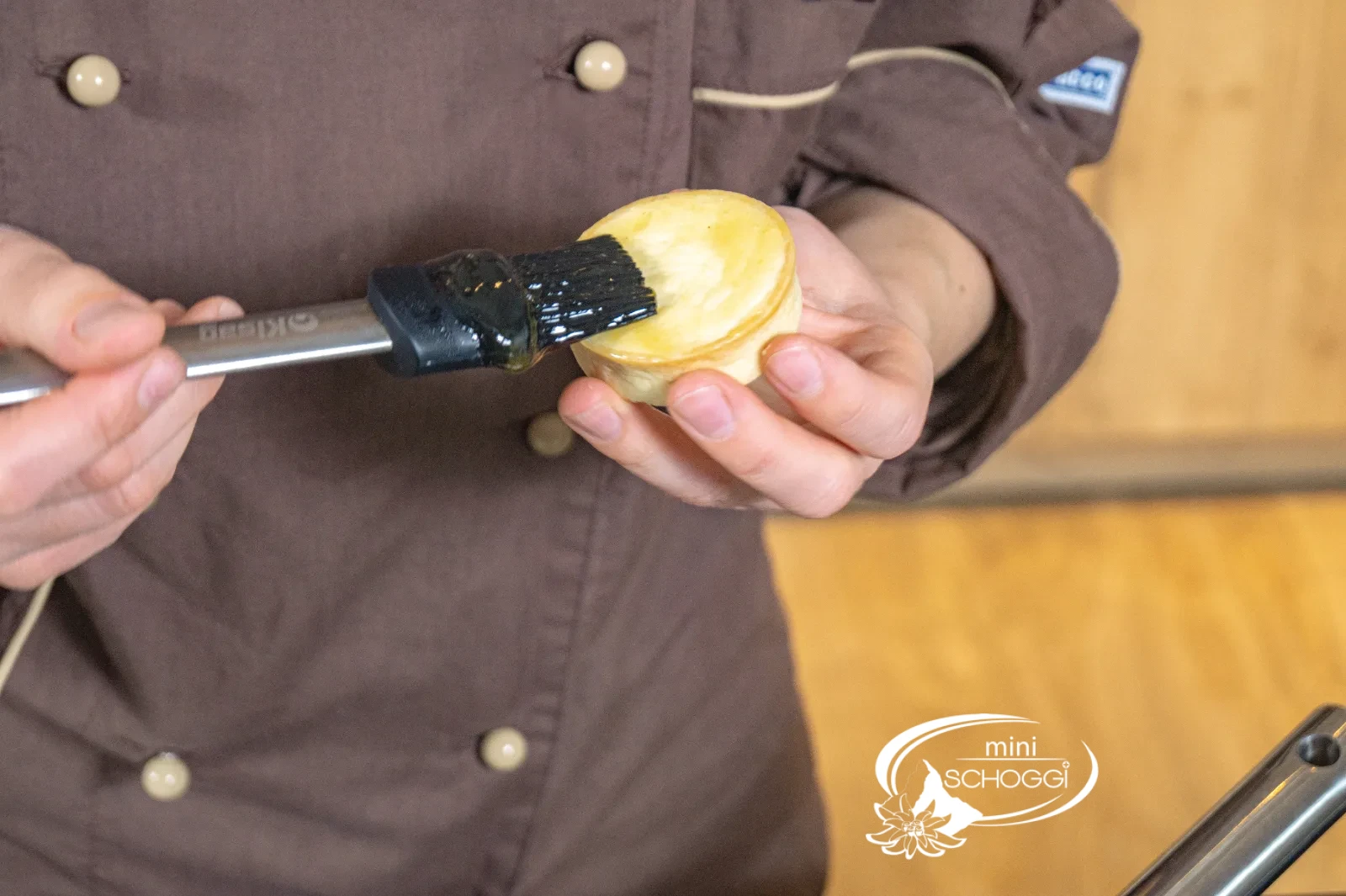 Una tarteletta viene spennellata con un sottile strato di confettura di albicocche con un pennello