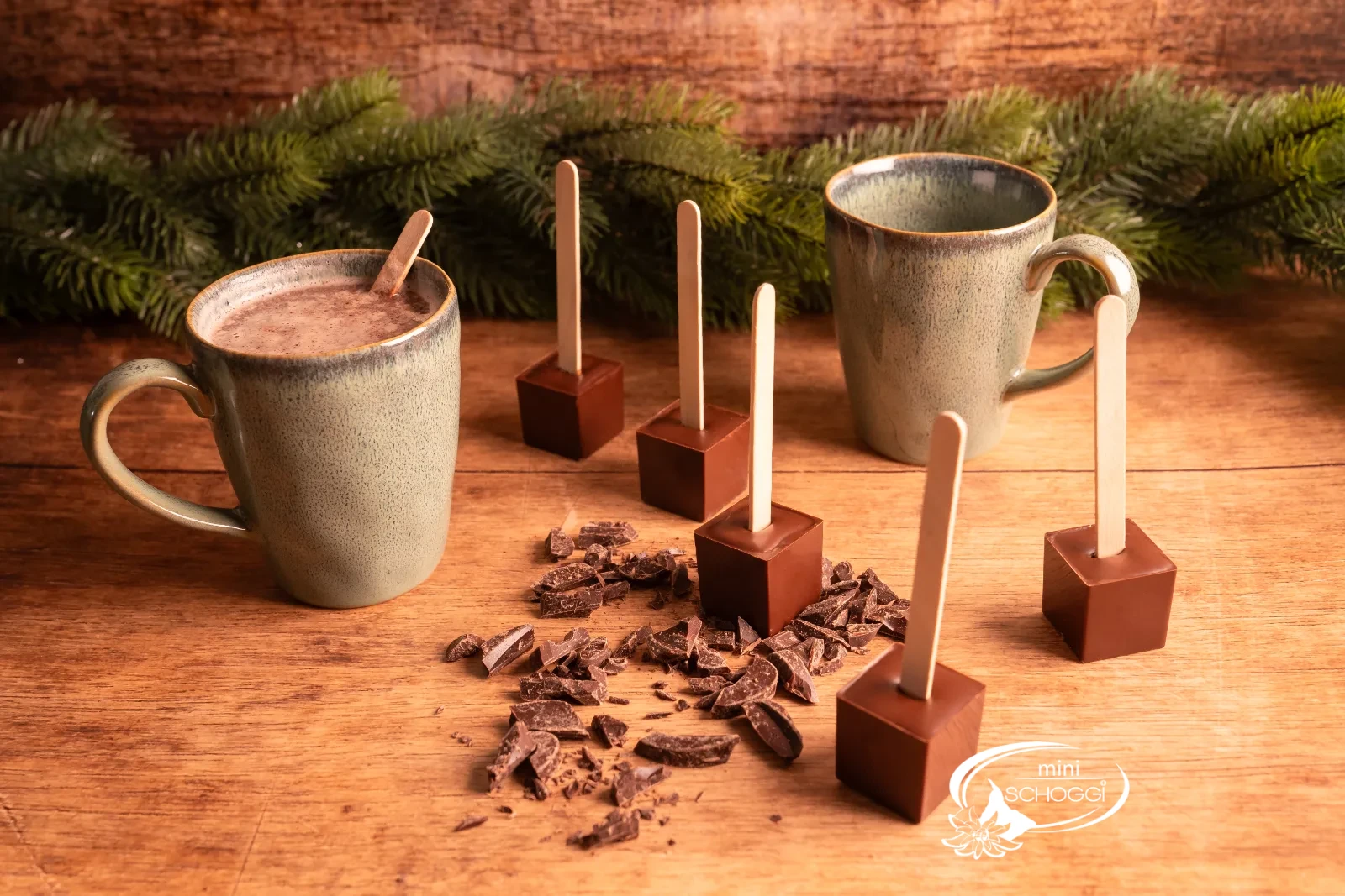 Ein Trinkschokoladen-Würfel am Stiel wird in eine Tasse heisse Milch getaucht