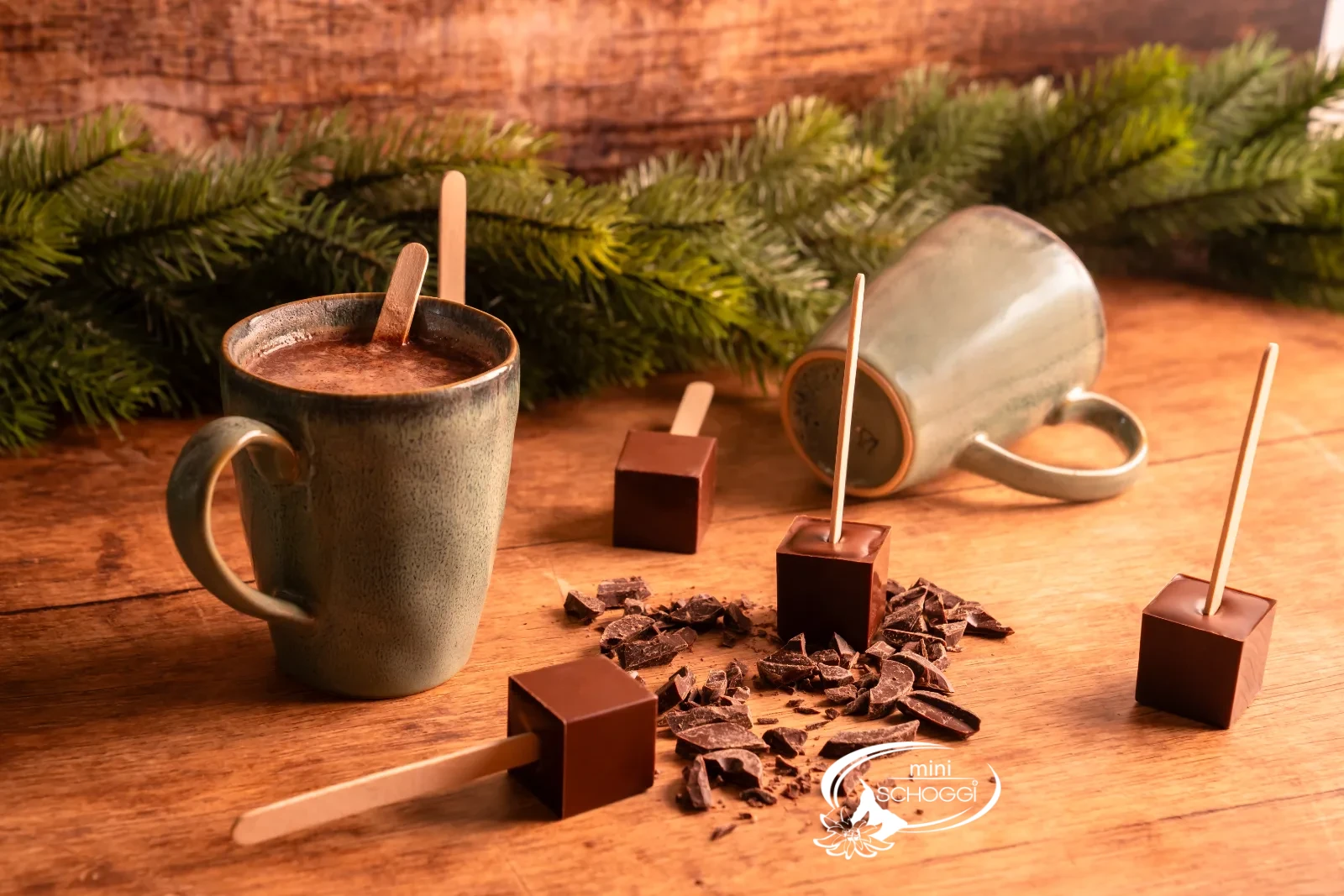 Ein Trinkschokoladen-Würfel am Stiel wird in eine Tasse heisse Milch getaucht
