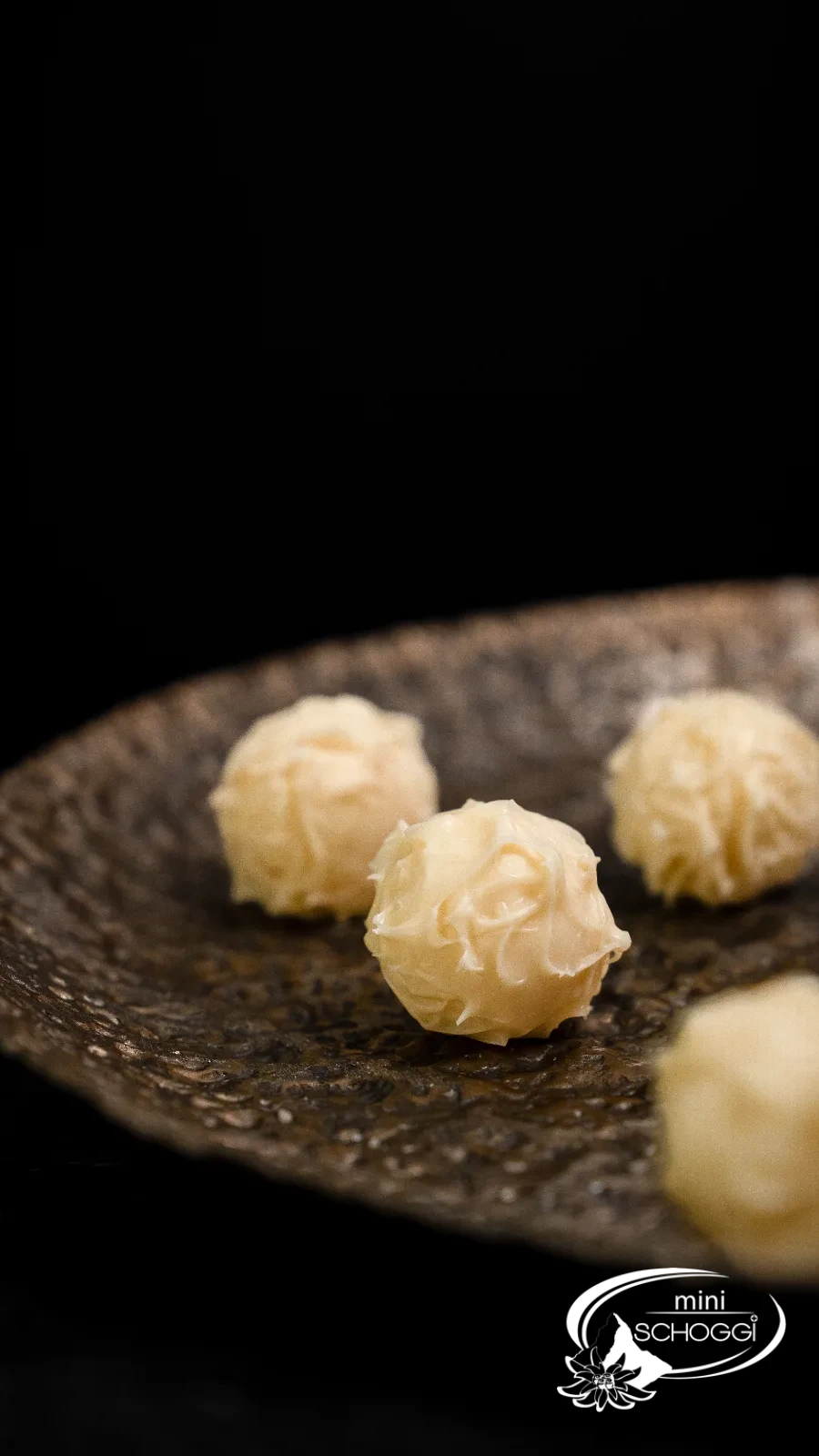 Trois truffes sur une pierre foncée, en arrière-plan la coupe pleine