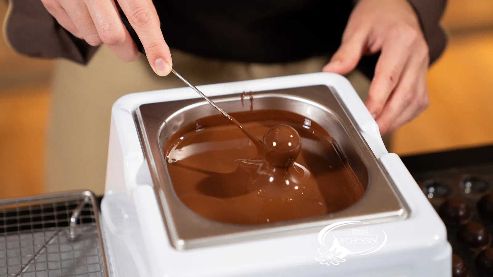 Eine Praline wird in temperierte Couverture getaucht