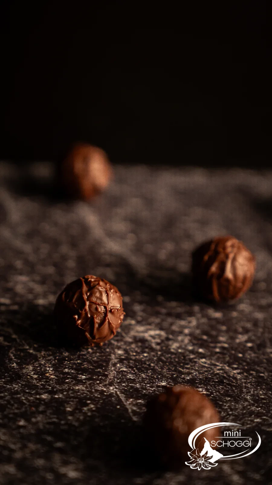 Trois truffes sur une pierre foncée, en arrière-plan la coupe pleine