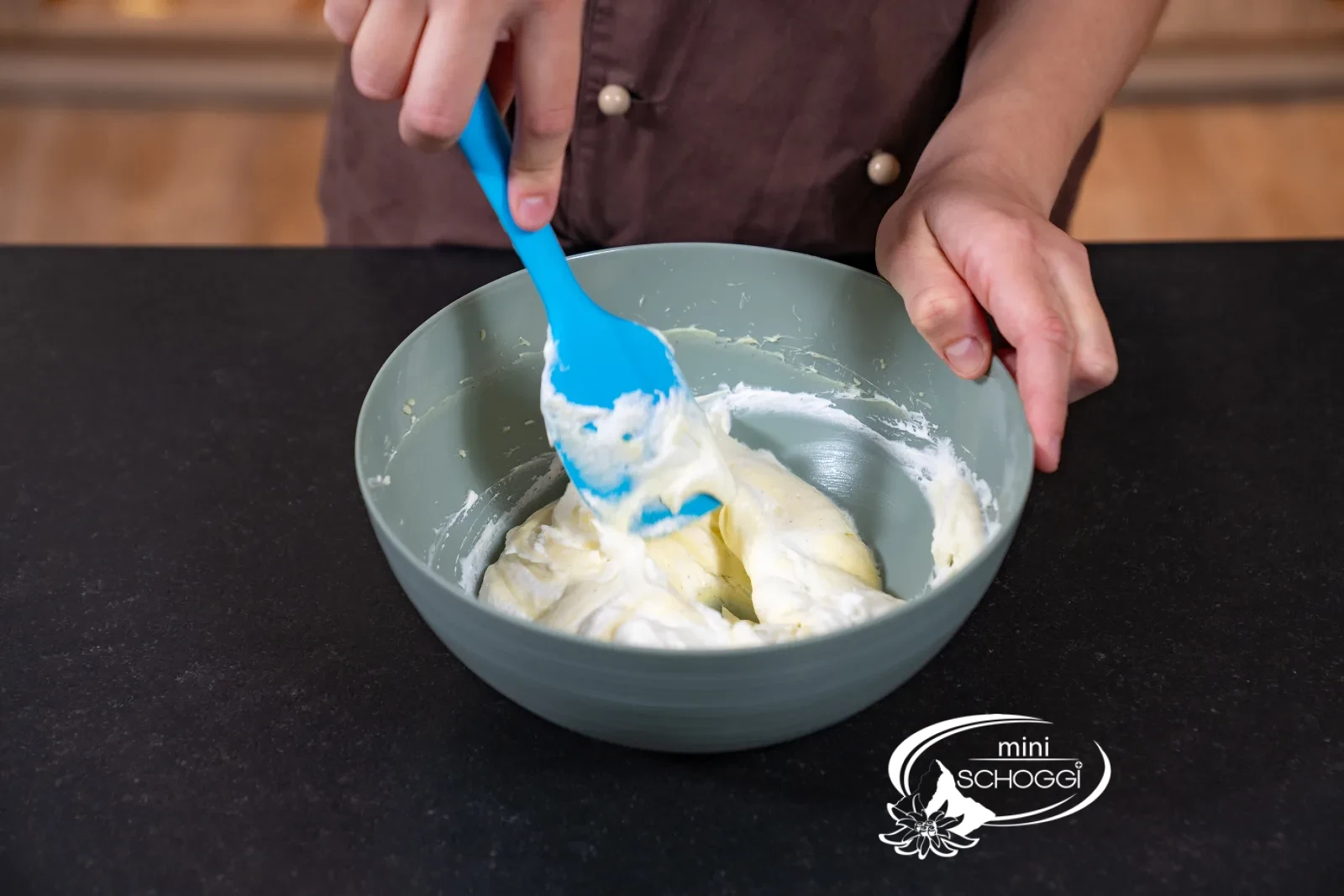 Geschlagener Rahm wird mit dem Teigschaber unter die glatte Vanillecreme gehoben