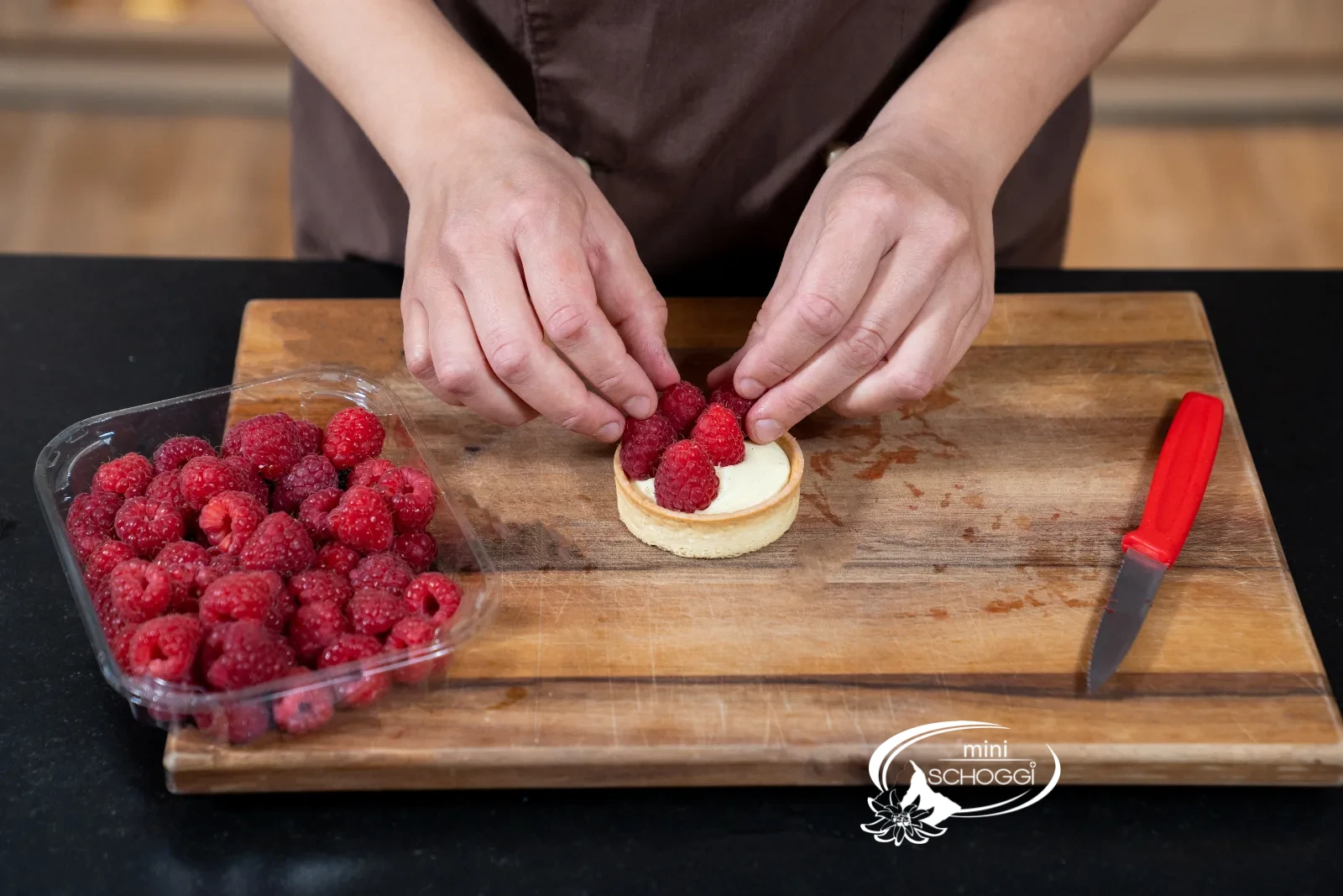 Fertige Törtchen werden mit Erdbeeren, Himbeeren und Heidelbeeren belegt
