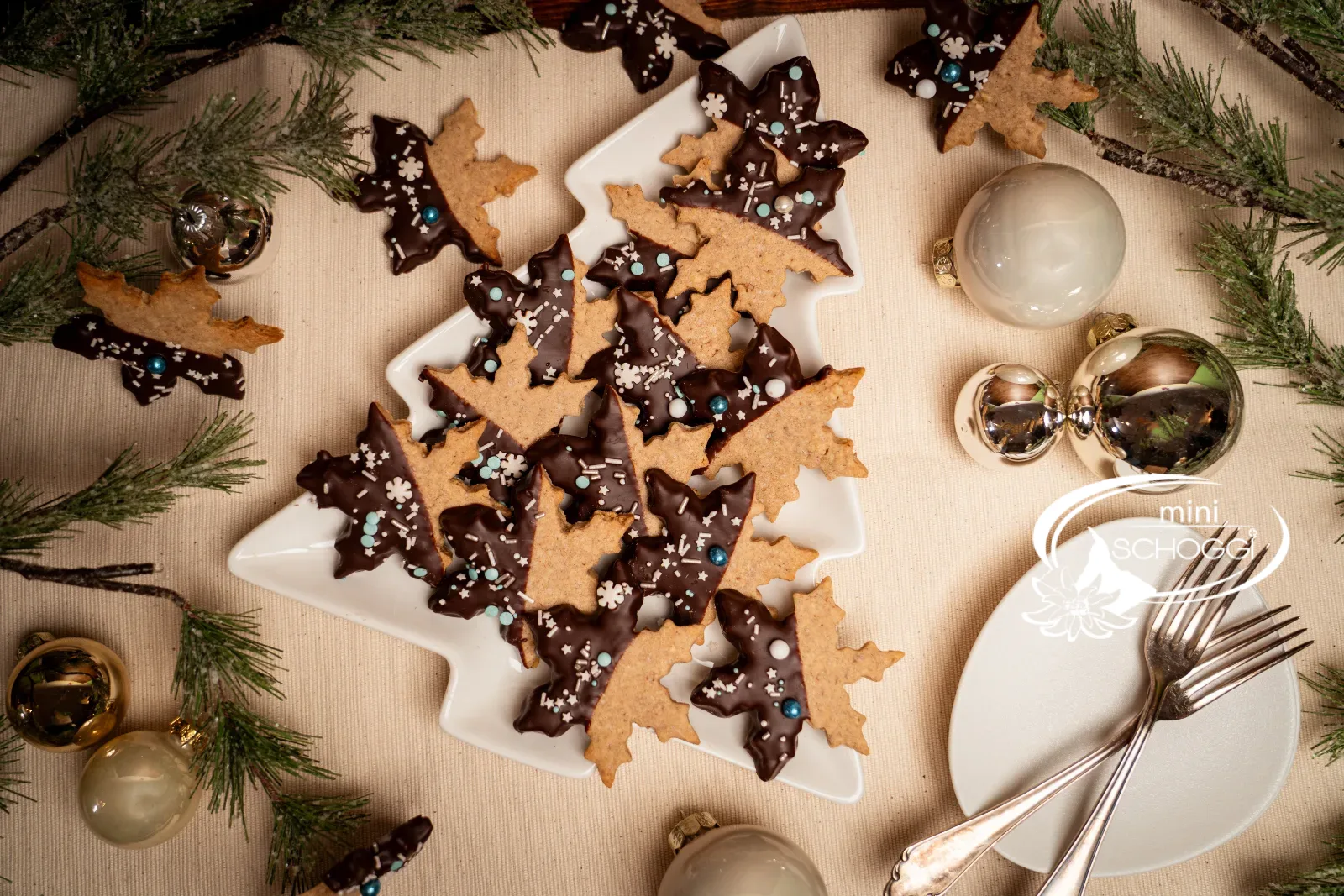 Weihnachtstisch mit Vollkorn Cookies, Christbaumkugeln und Tellern