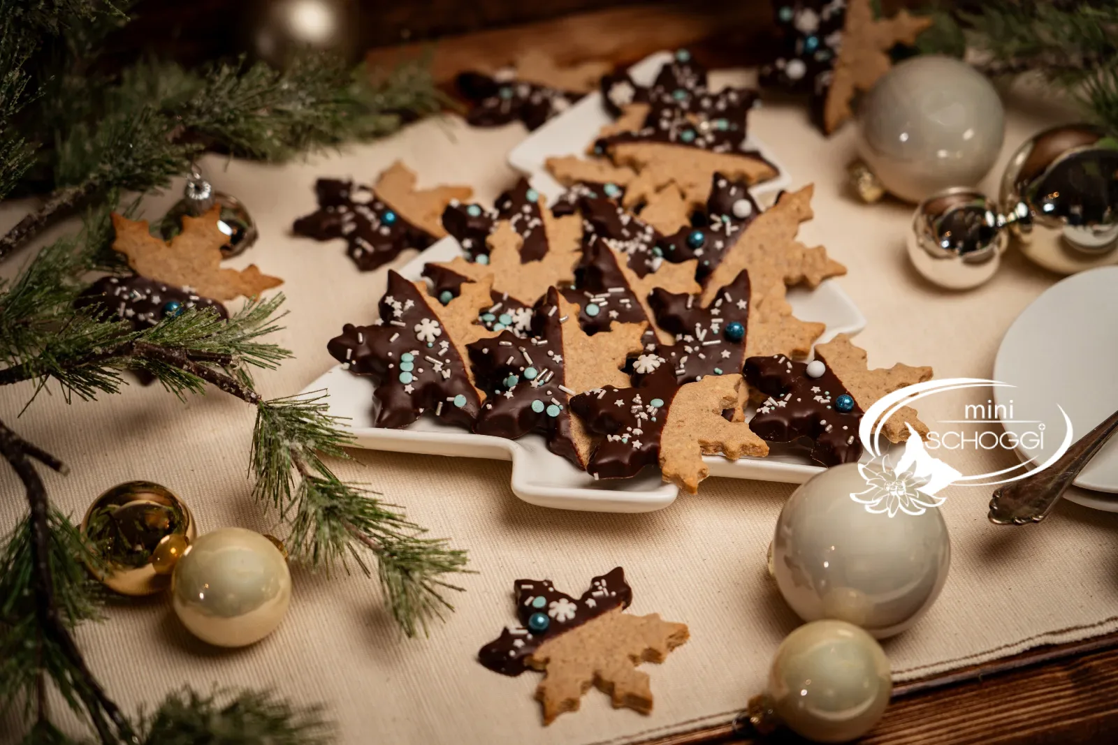Schneestern-Cookies auf einer Tannenbaum-Platte mit Christbaumkugeln