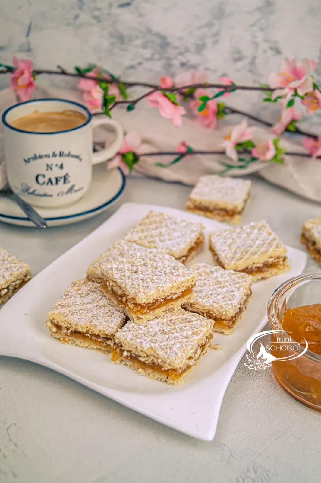 Cuoricini waffel con zucchero a velo su un tagliere di legno accanto a una tazza di caffè e confettura di albicocche