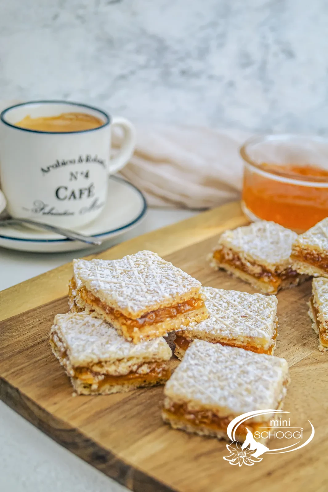 Cuoricini waffel con zucchero a velo su un tagliere di legno accanto a una tazza di caffè e confettura di albicocche