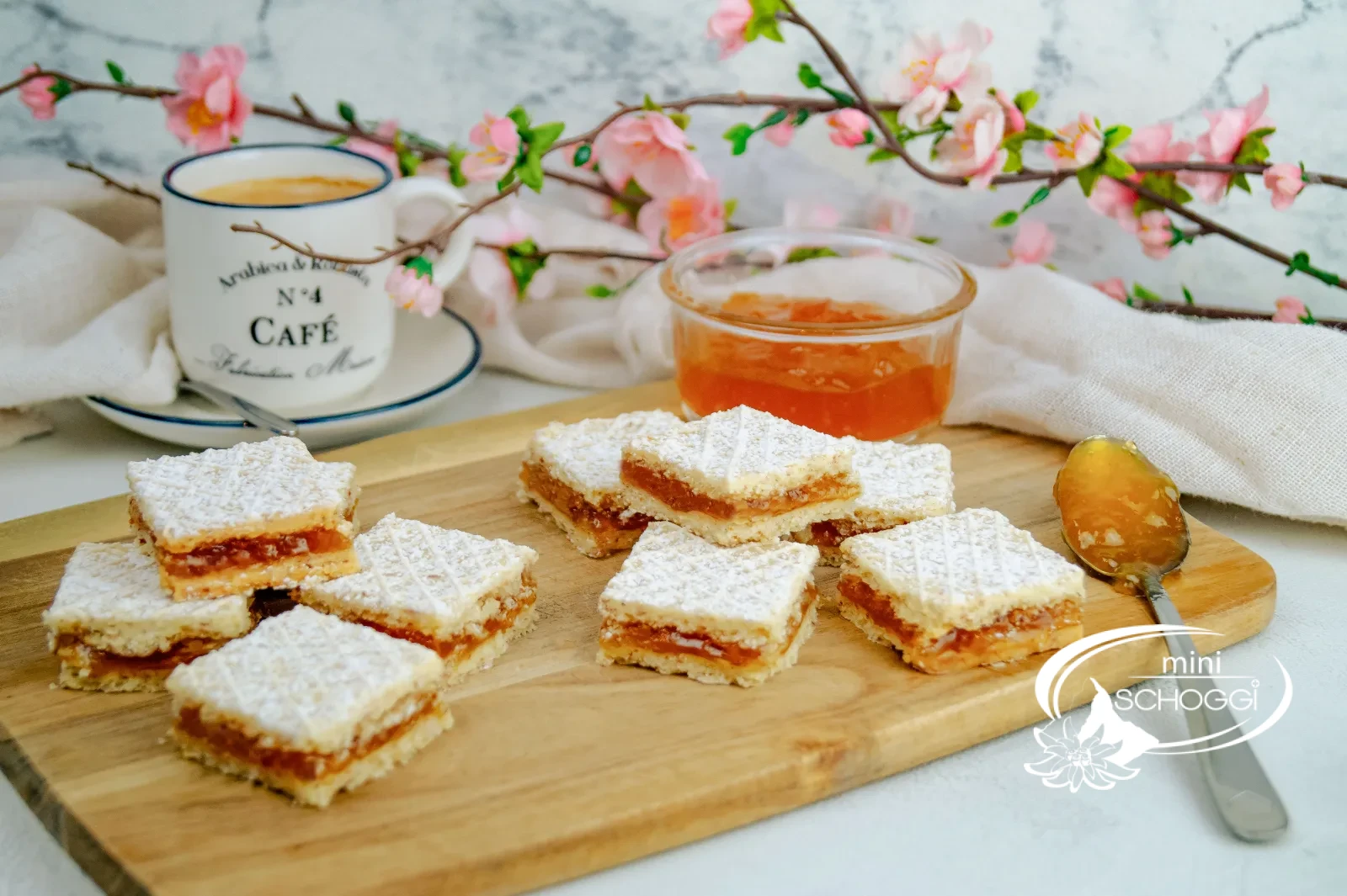 Cuoricini waffel con zucchero a velo su un tagliere di legno accanto a una tazza di caffè e confettura di albicocche