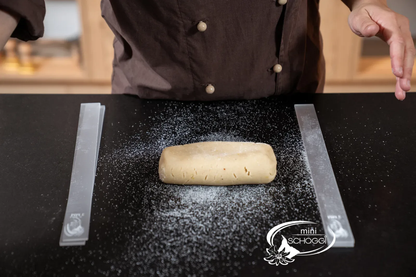 Bloc de pâte entre les rouleaux à pâtisserie sur une surface farinée