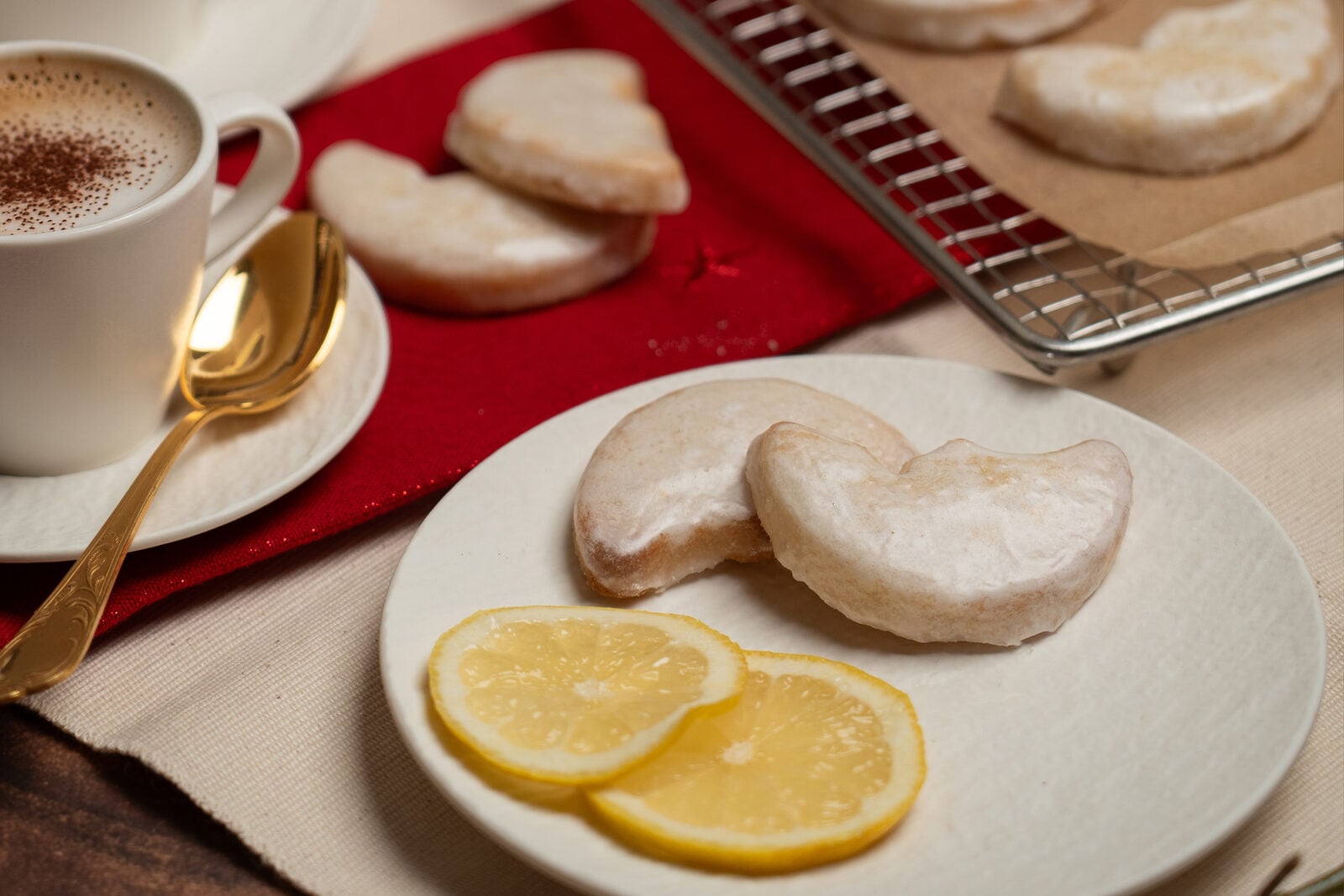 Citron möndli glacés sur une grille à gâteau à côté d’un cappuccino et d’une bougie allumée