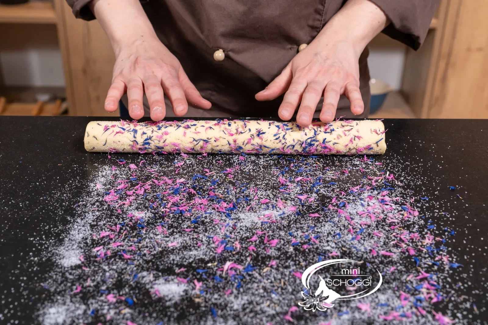 Il rotolo di impasto viene rotolato sopra il mix di zucchero e fiori